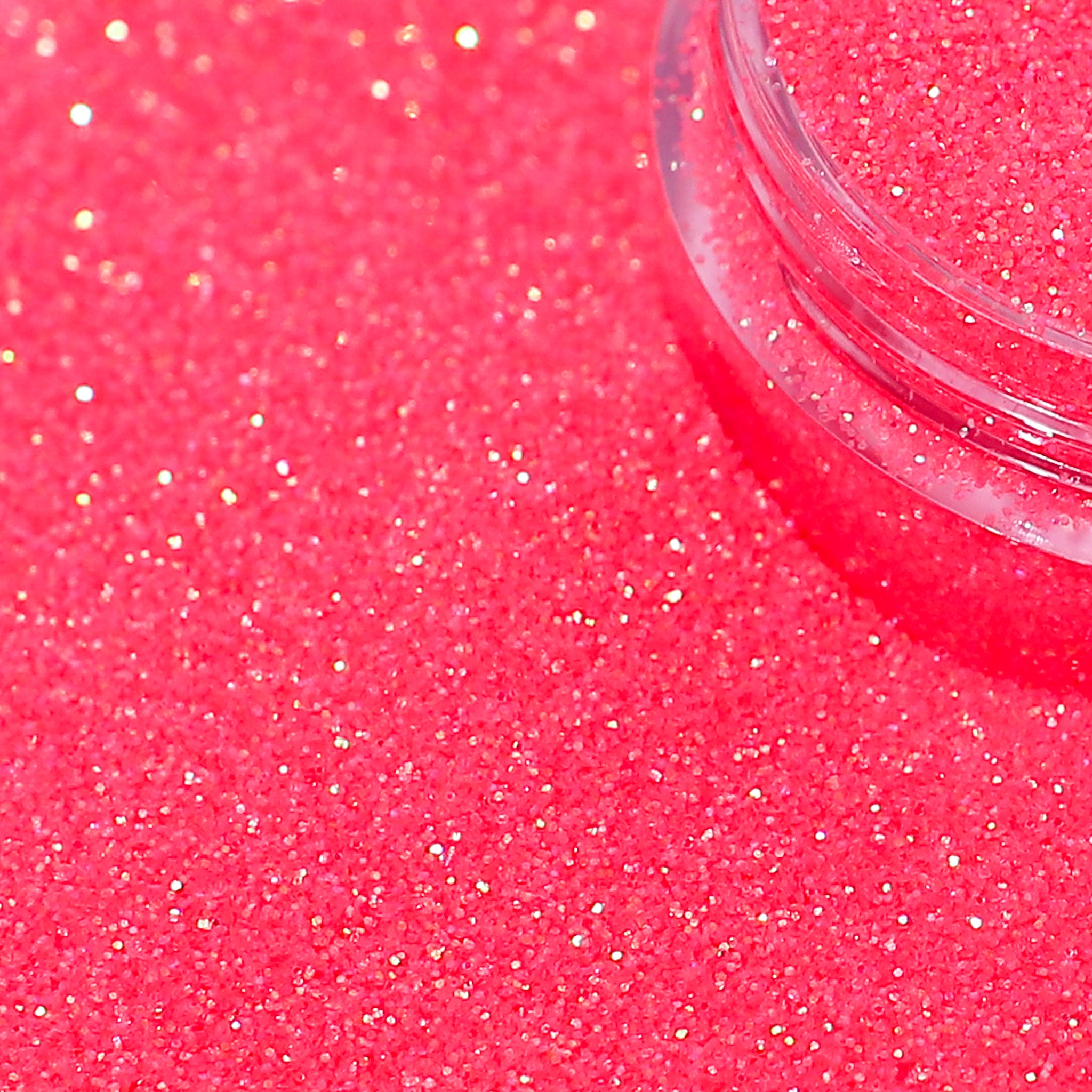 Close-up of pink glitter with a clear container on a pink background