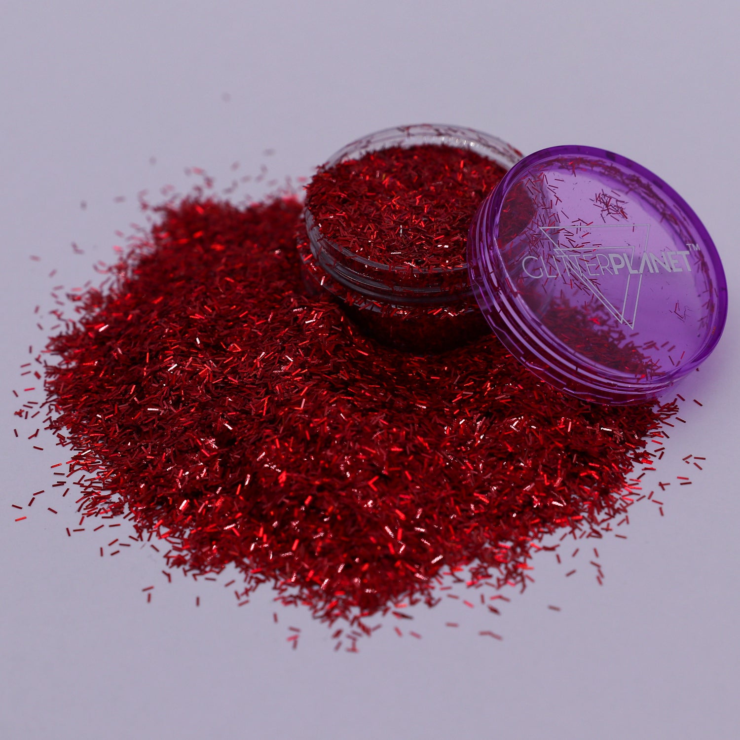 Red glitter spilling out of a clear container labeled &
