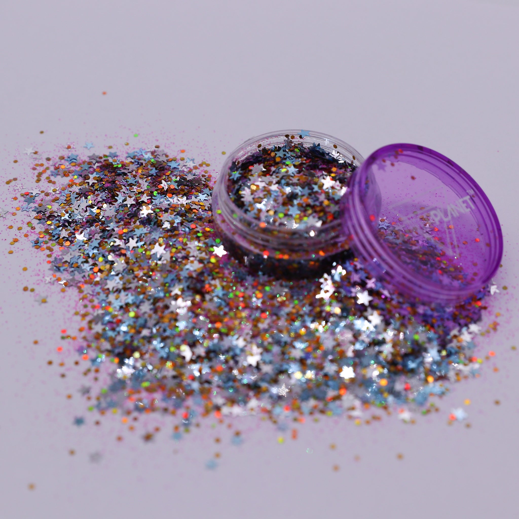 Multicolored glitter spilling out of a purple container on a light gray background