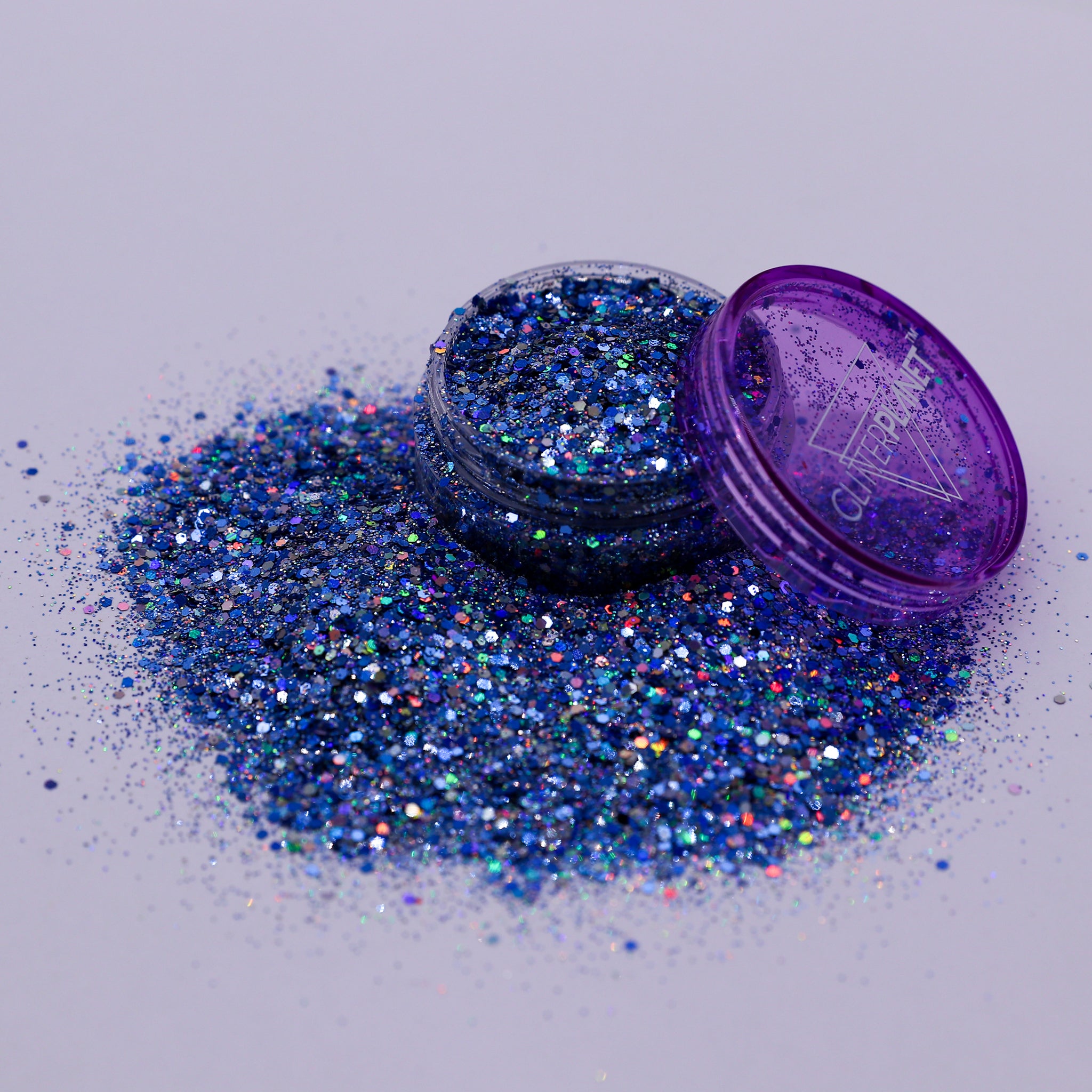Blue glitter with a purple lid on a light gray background