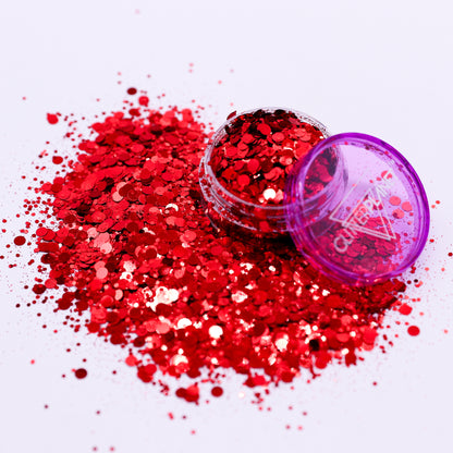 Red glitter spilling out of a purple container on a white background
