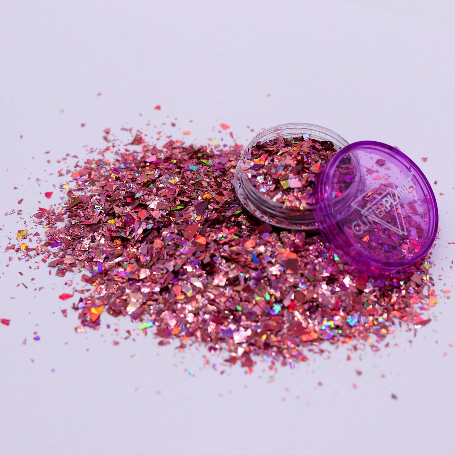 Pink glitter with a purple container on a light gray background