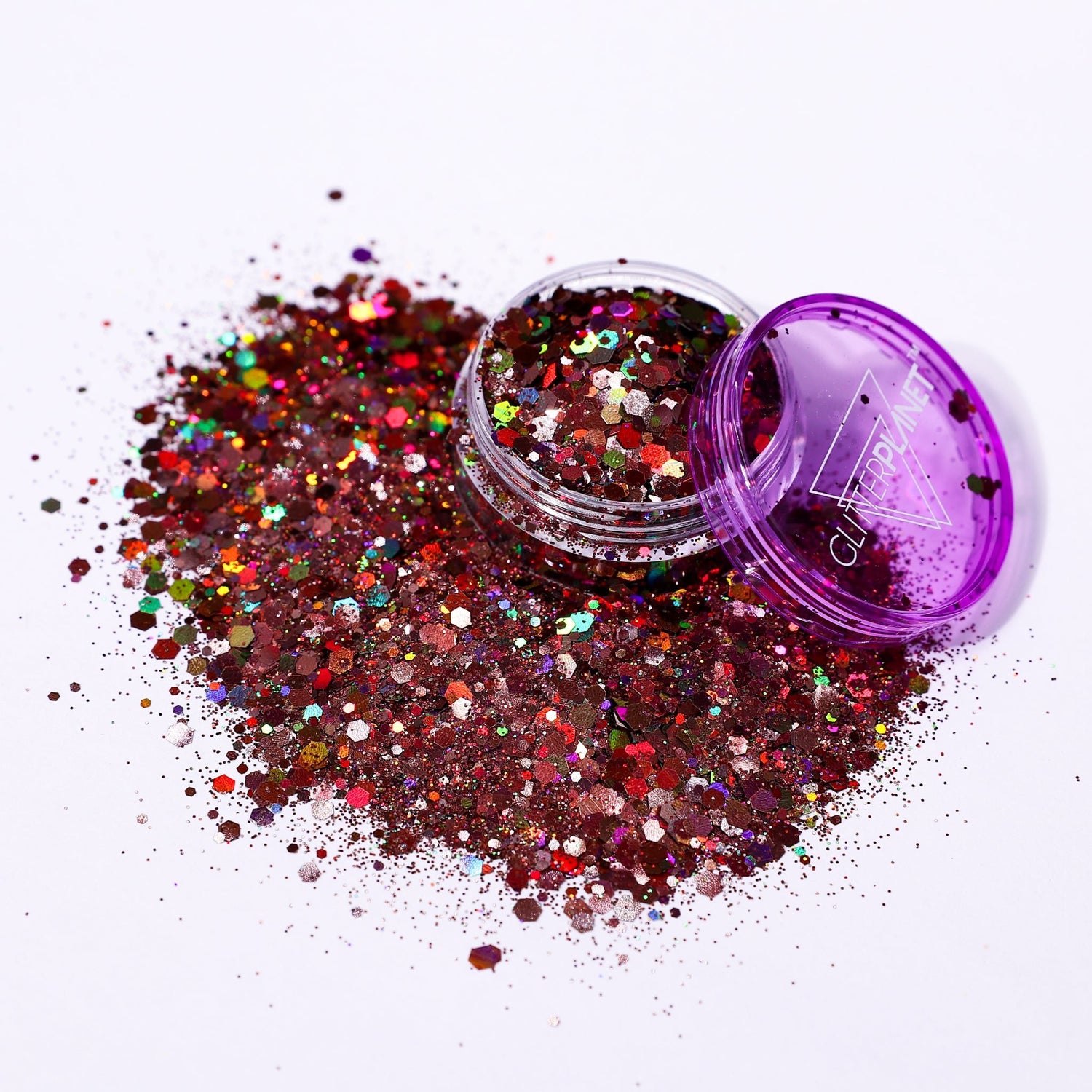 Multicolored glitter spilling out of a purple container on a white background