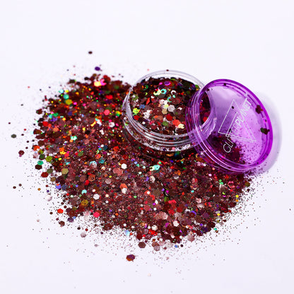 Multicolored glitter spilling out of a purple container on a white background