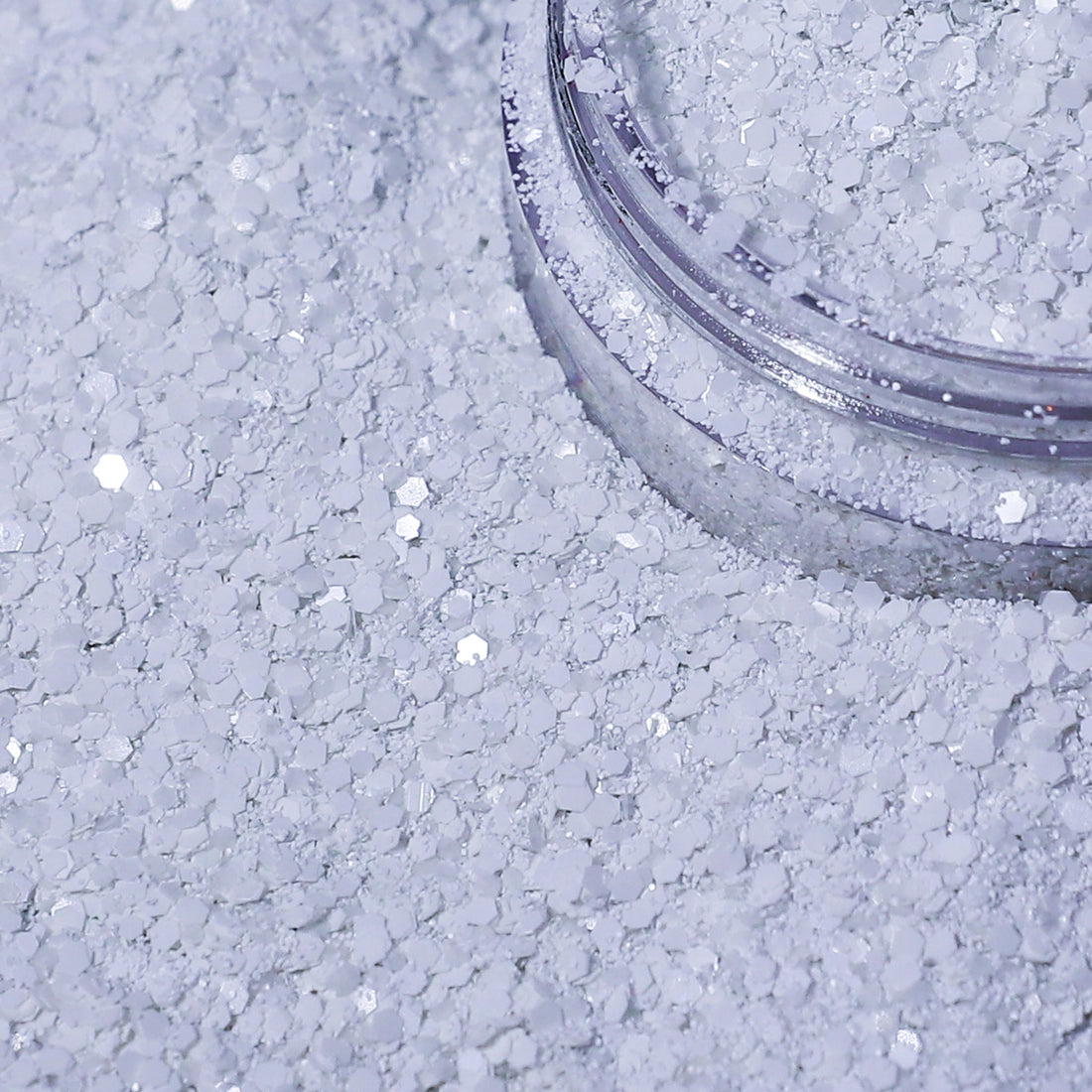 Close-up of a container of white glitter on a textured surface.