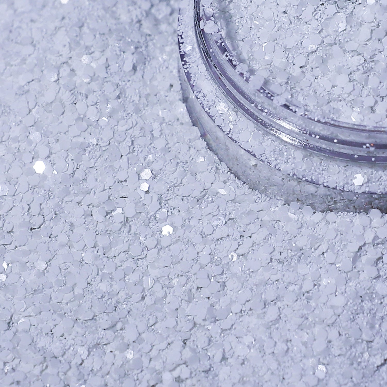 Close-up of a container of white glitter on a textured surface.