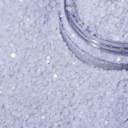 Close-up of a container of white glitter on a textured surface.