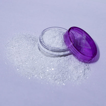 Open container of glitter with purple lid on a light purple background