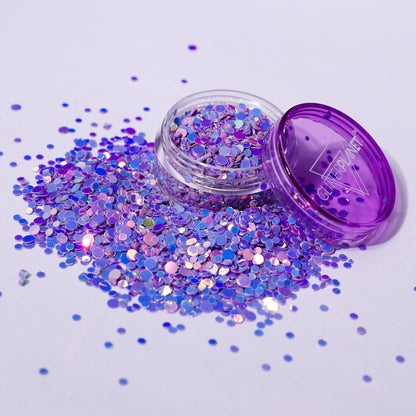Open container of purple glitter with scattered glitter on a light purple background