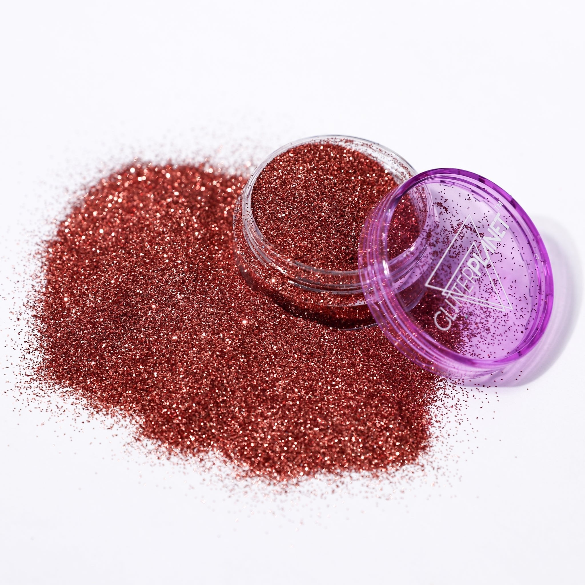 bronze glitter in an open container with a purple lid on a white background