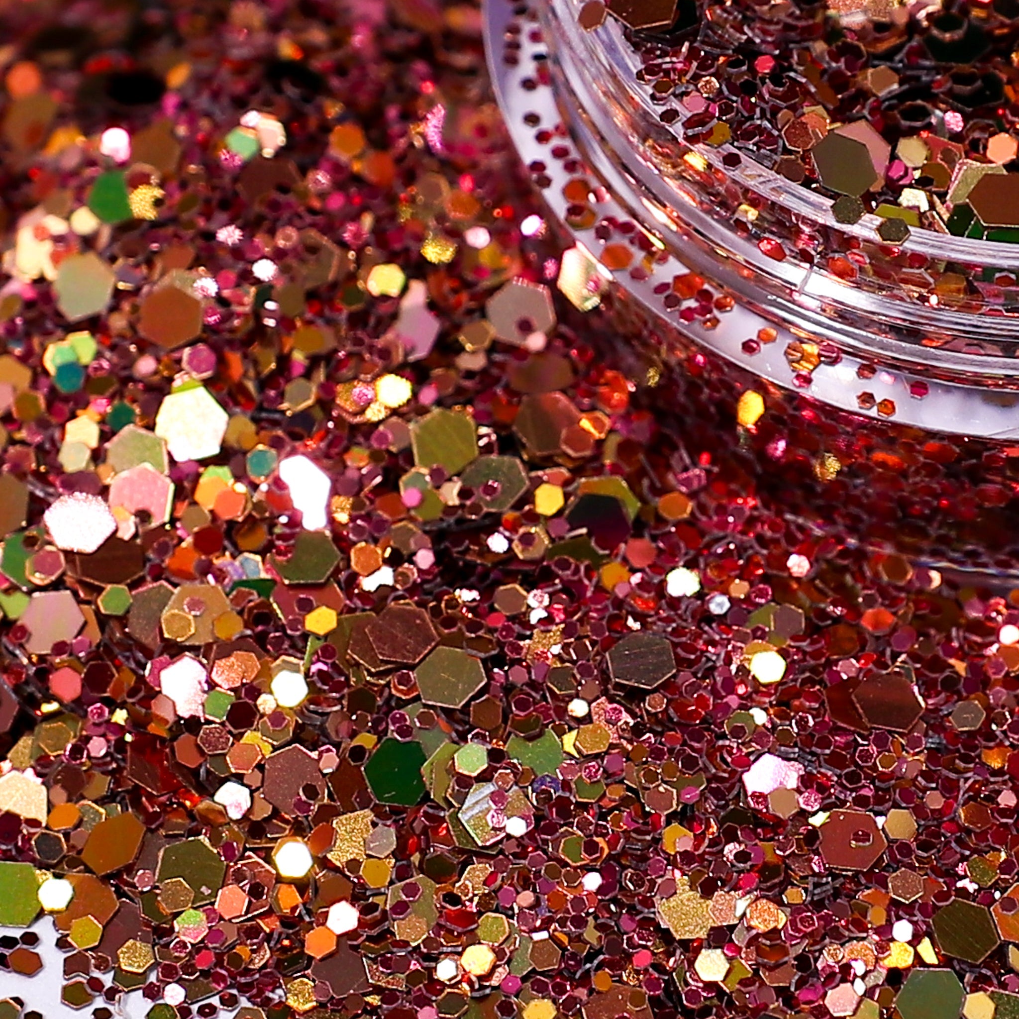 Close-up of rose gold glitter with a clear container partially filled with glitter.