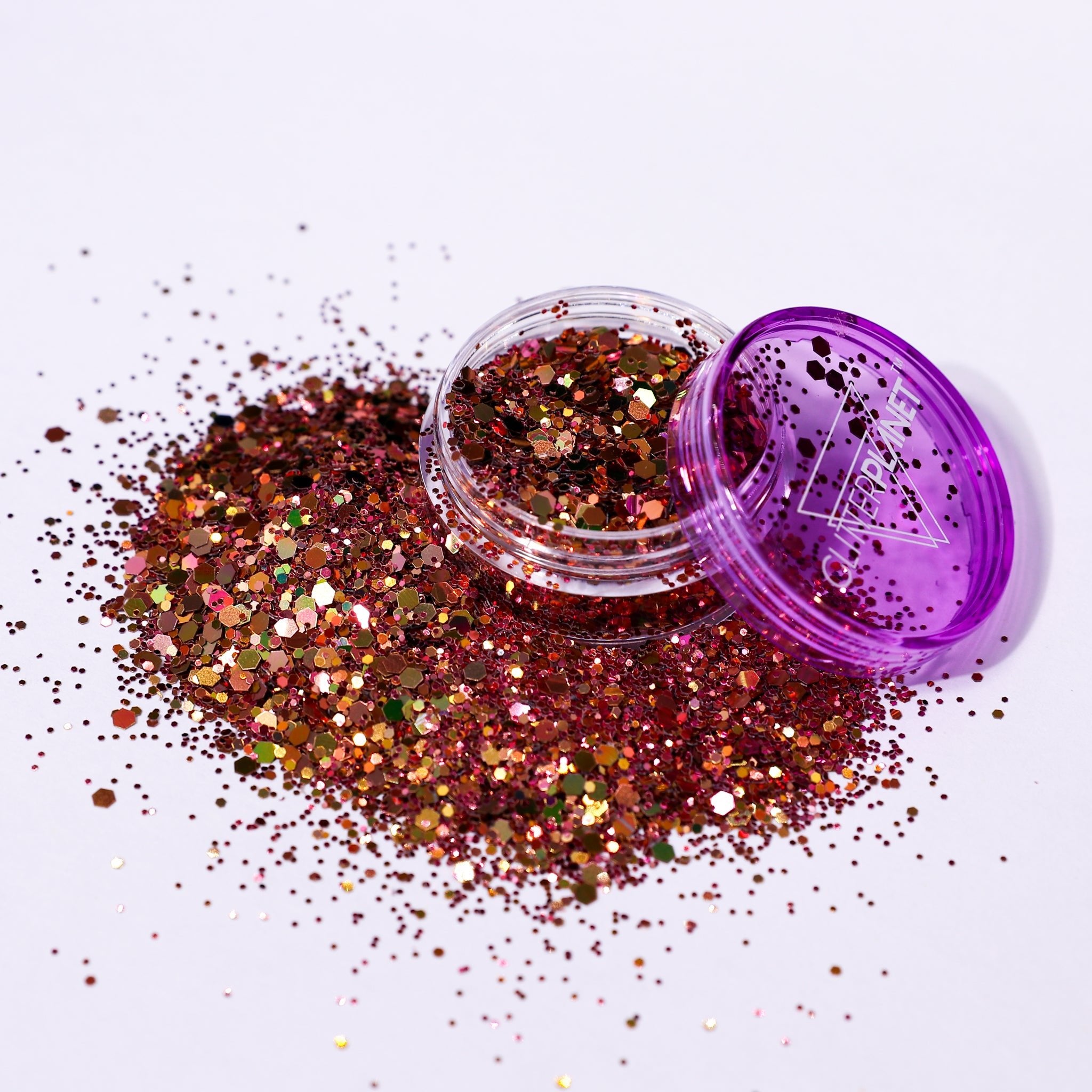 Open container of glitter with purple lid on a white background