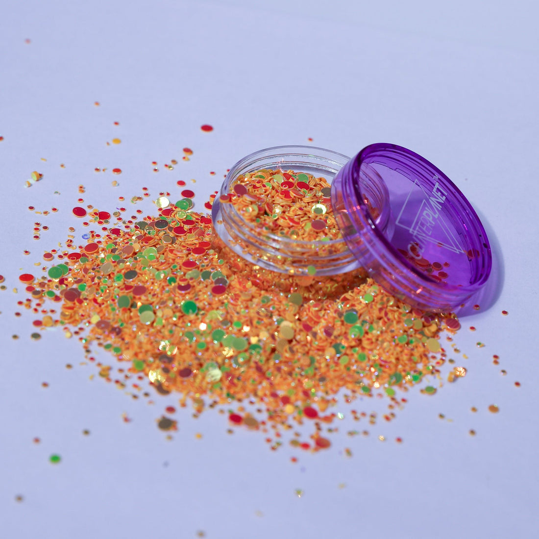Colorful glitter spilling out of a purple container on a light blue background