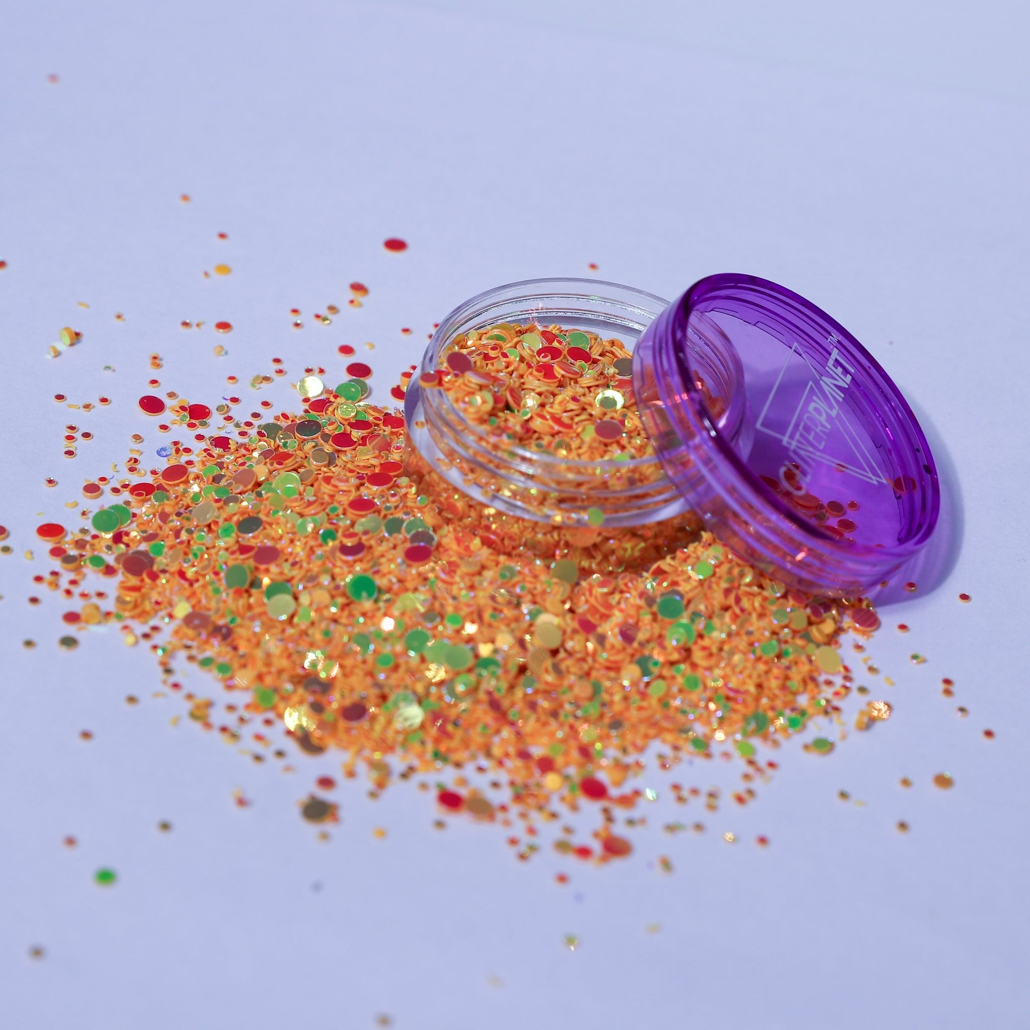 Colorful glitter spilling out of a purple container on a light blue background