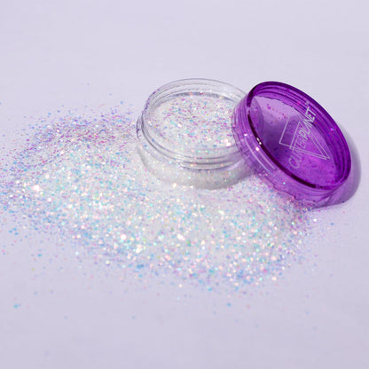 Open container of glitter with purple lid on a light gray background