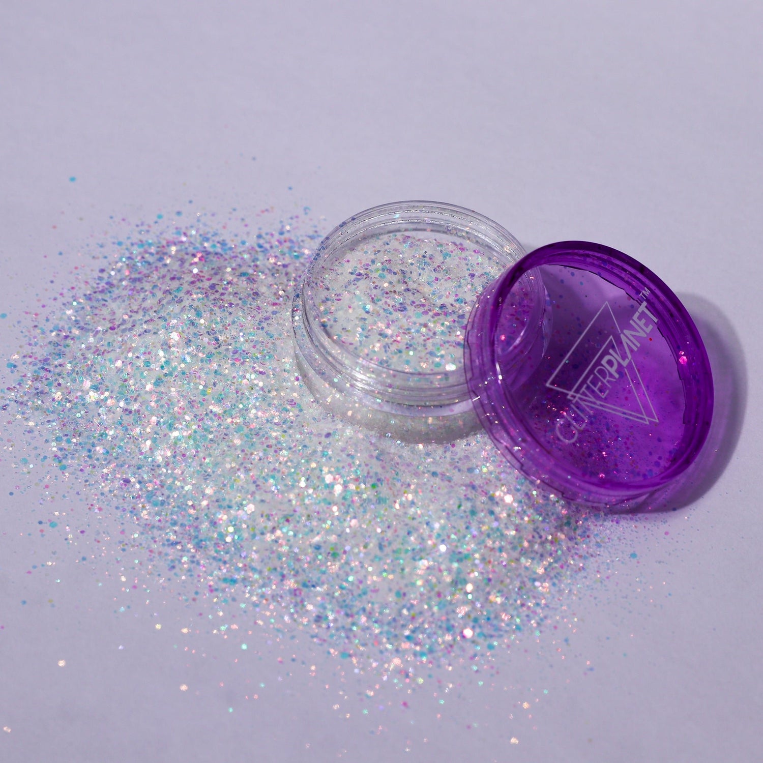 Open container of glitter with purple lid on a light gray background