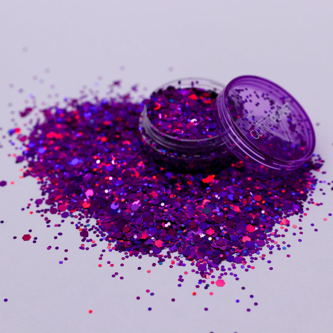 Purple glitter with an open container on a light gray background