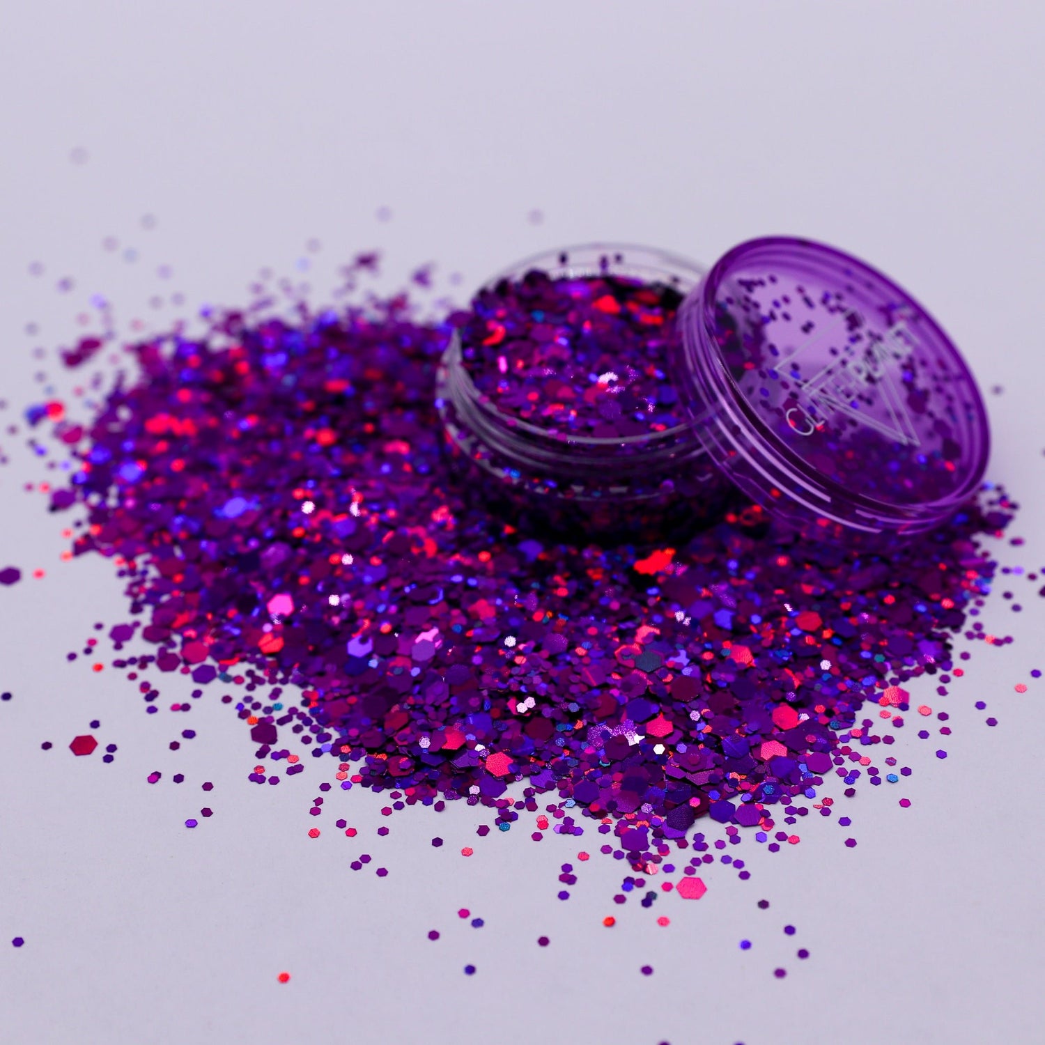 Purple glitter with an open container on a light gray background