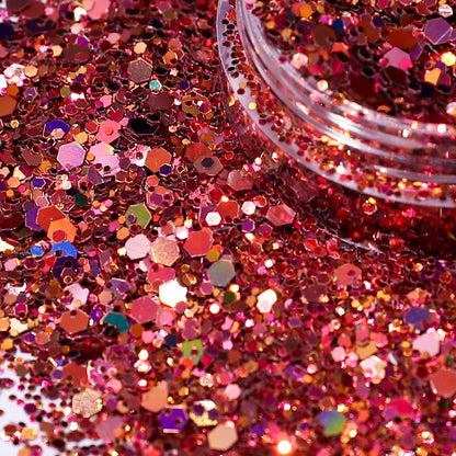 Close-up of pink glitter with a clear container partially filled with glitter.