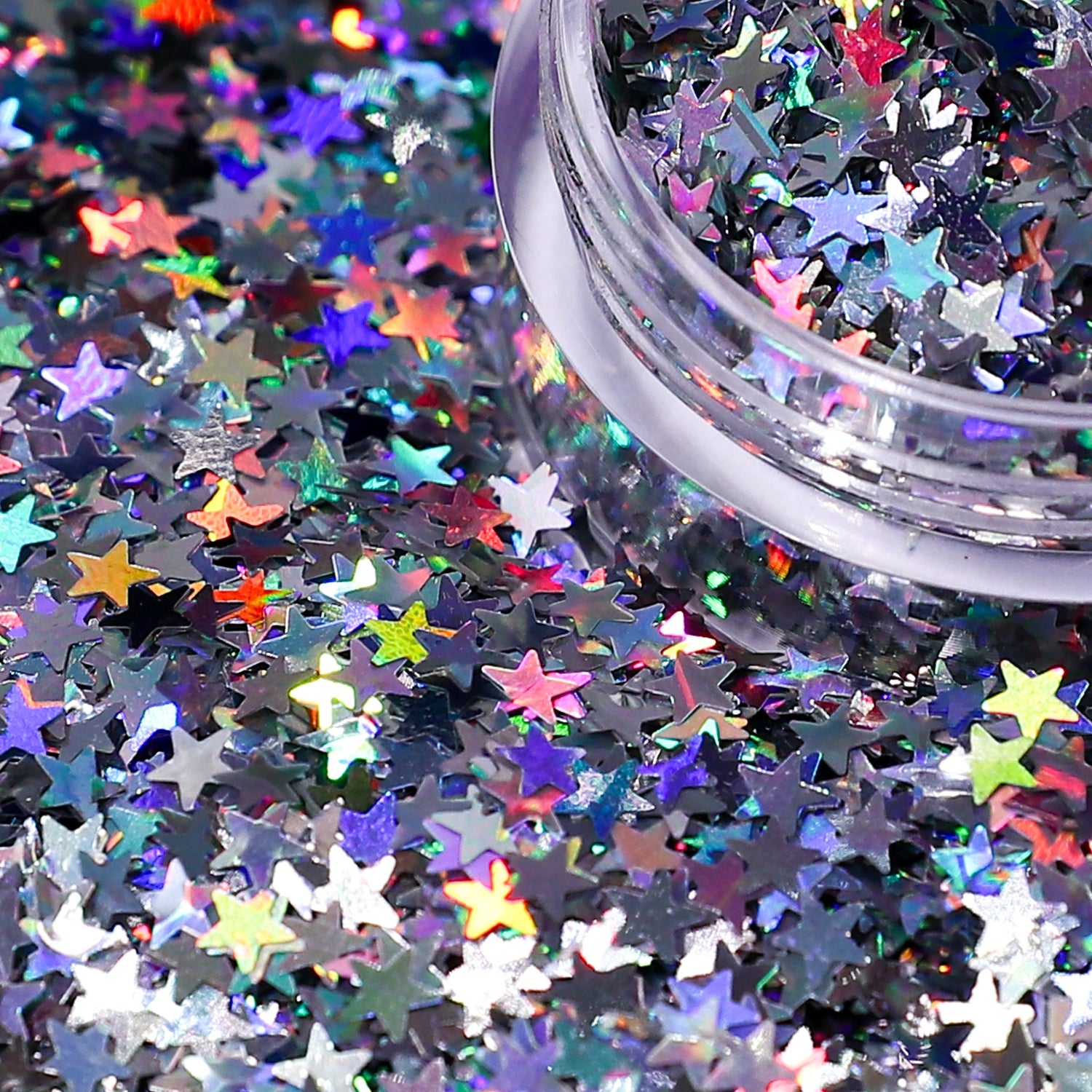 Colorful star-shaped glitter scattered on a black background with a container of glitter.