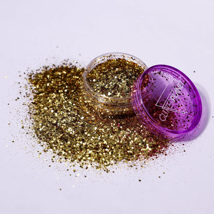 Gold glitter spilling out of a purple container with &