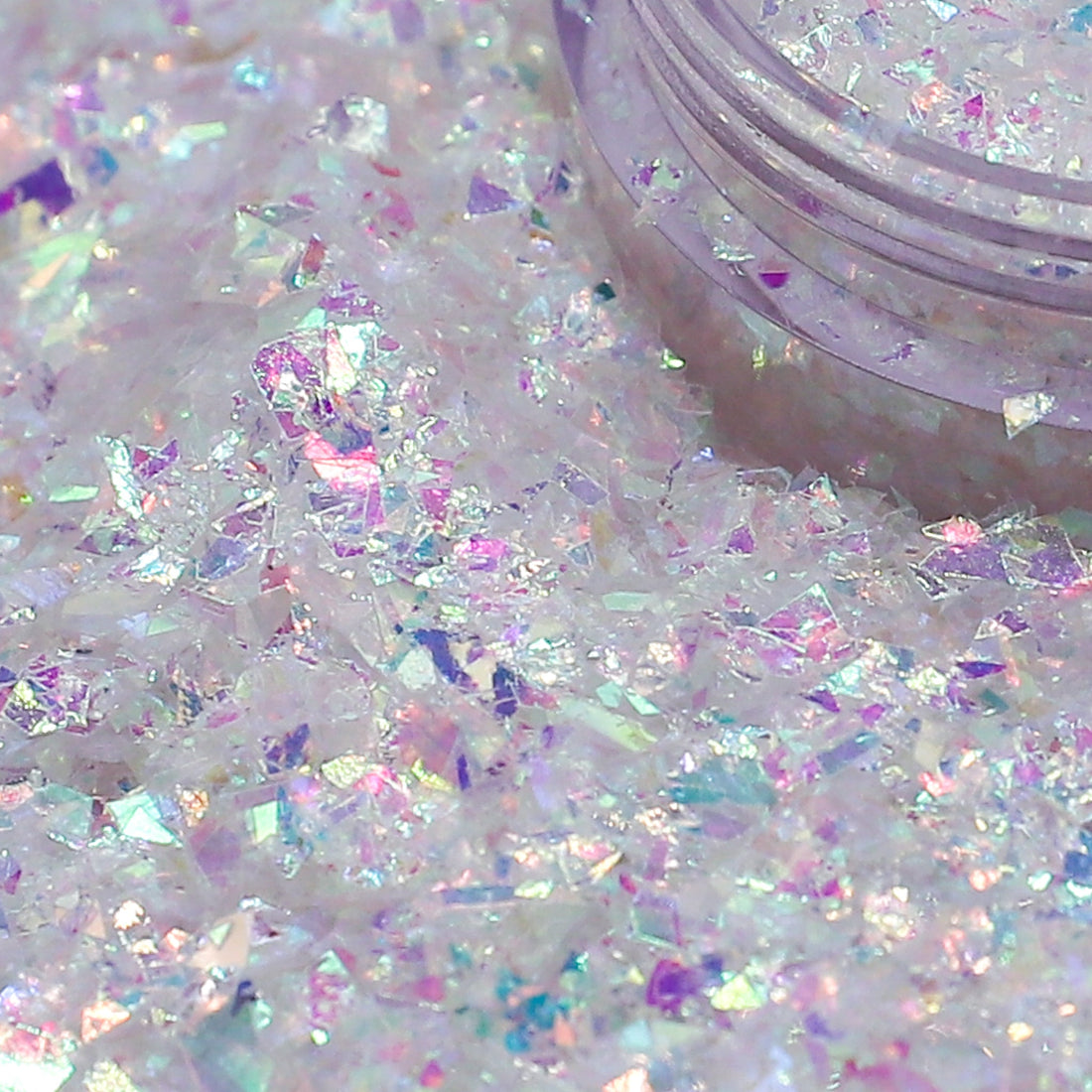 Iridescent glitter on a white background with a container of glitter.