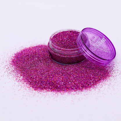Purple glitter in an open container with spilled glitter on a white background