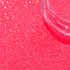 Close-up of pink glitter with a clear container on a pink background