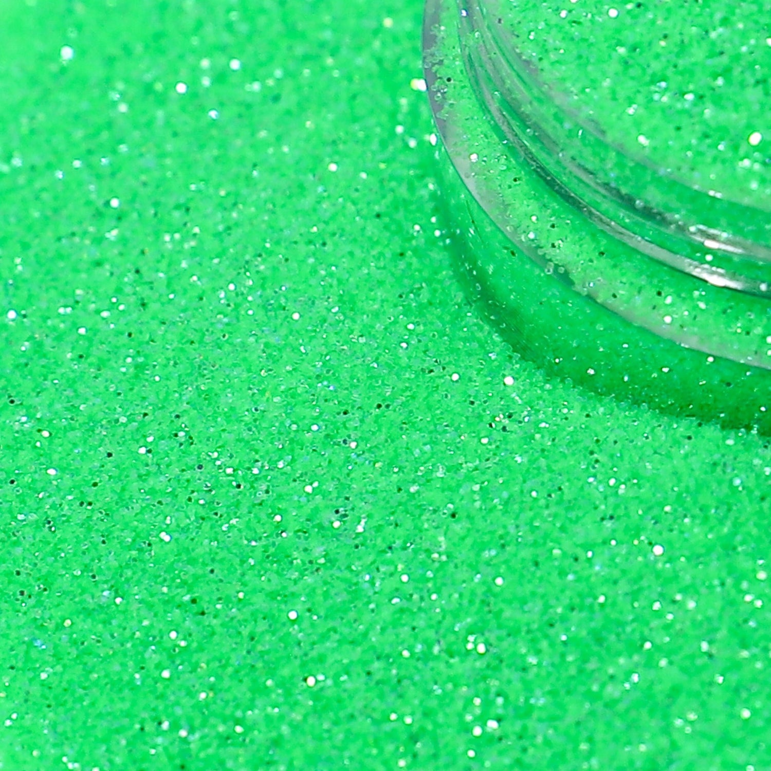Green glitter with a clear container partially filled with glitter.