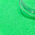 Green glitter with a clear container partially filled with glitter.