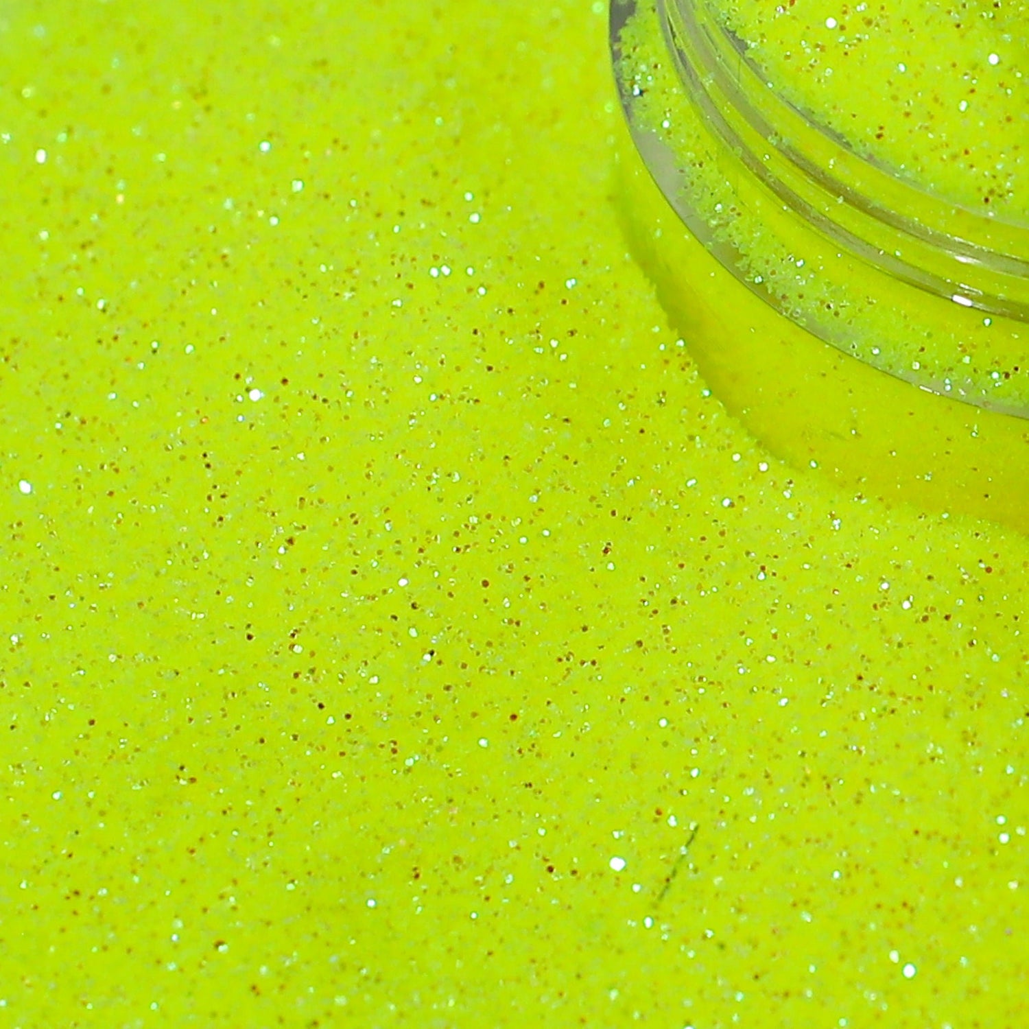 Close-up of bright yellow glitter with a clear container partially filled with glitter.
