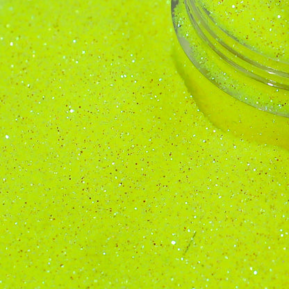 Close-up of bright yellow glitter with a clear container partially filled with glitter.