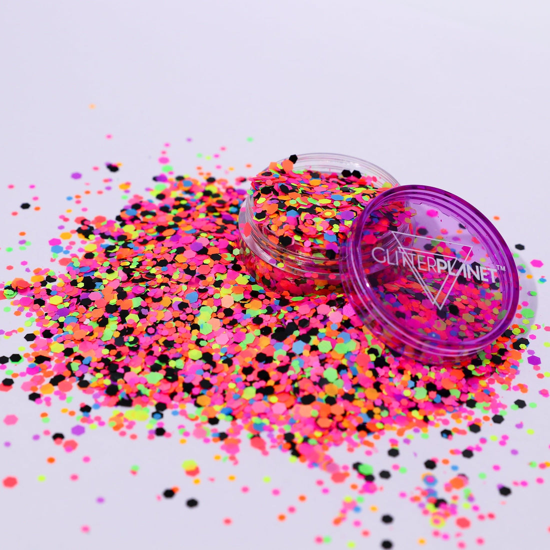 Colorful glitter scattered on a white background with a container labeled &