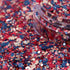Colorful glitter with red, blue, and pink hex shapes spilling out of a container.