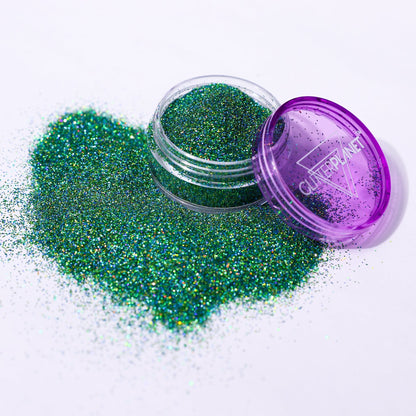 Green glitter in an open container with a purple lid on a white background