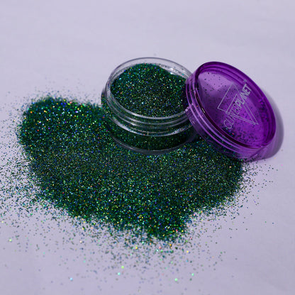 Green glitter spilling out of a purple container labeled &