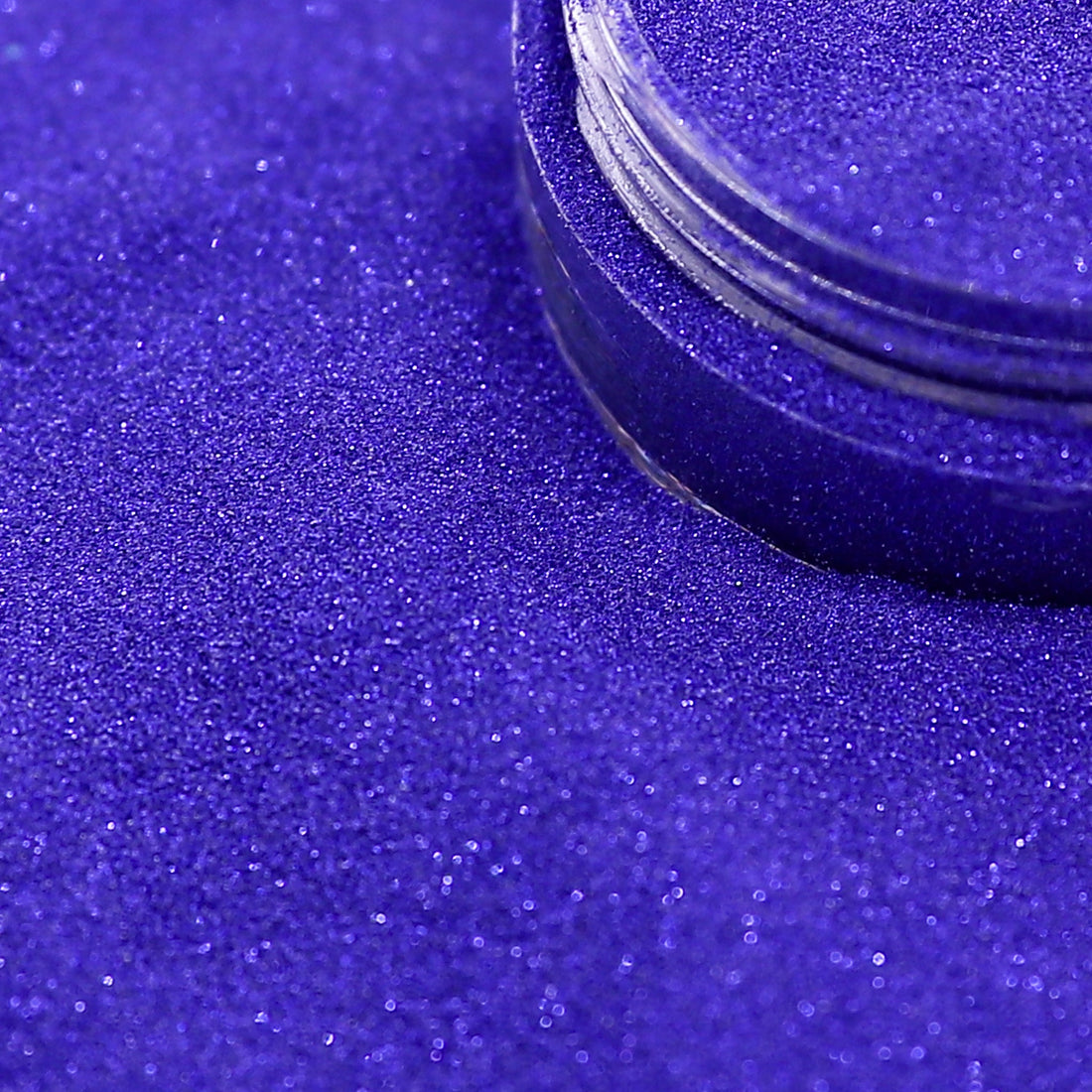 navy blue glittery powder with a container on a purple background