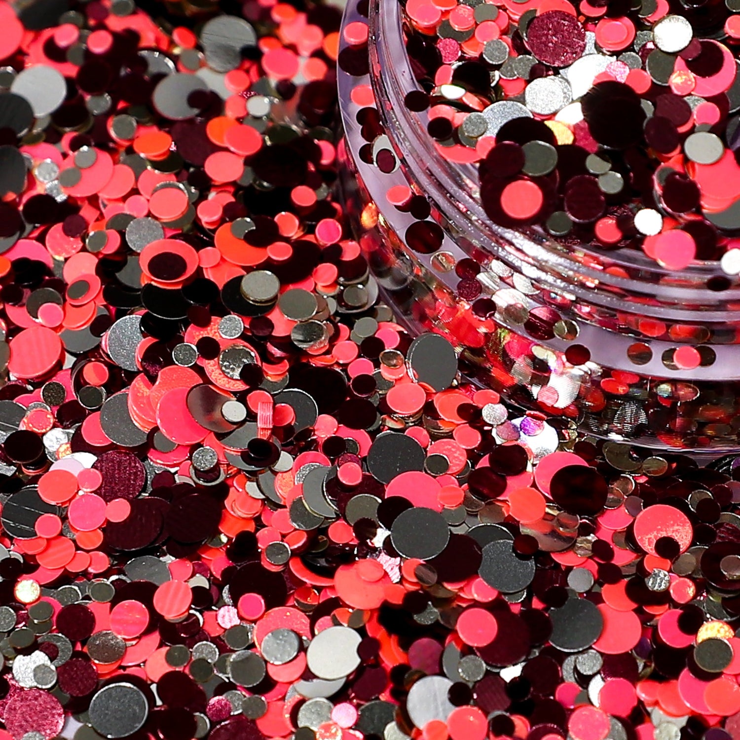 Close-up of orange, black, and silver round confetti with a clear container.