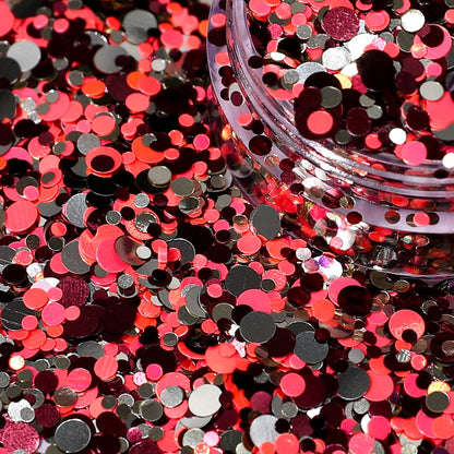 Close-up of orange, black, and silver round confetti with a clear container.