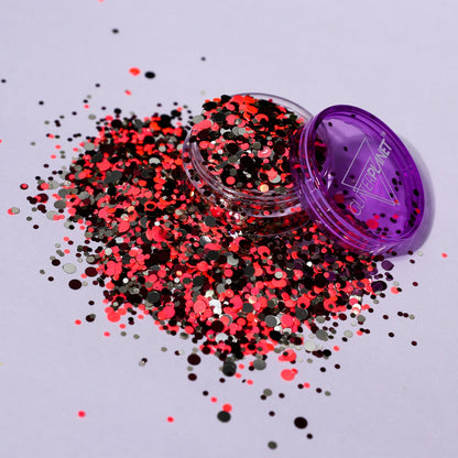 Open container of multicolored glitter with purple lid on a light gray background