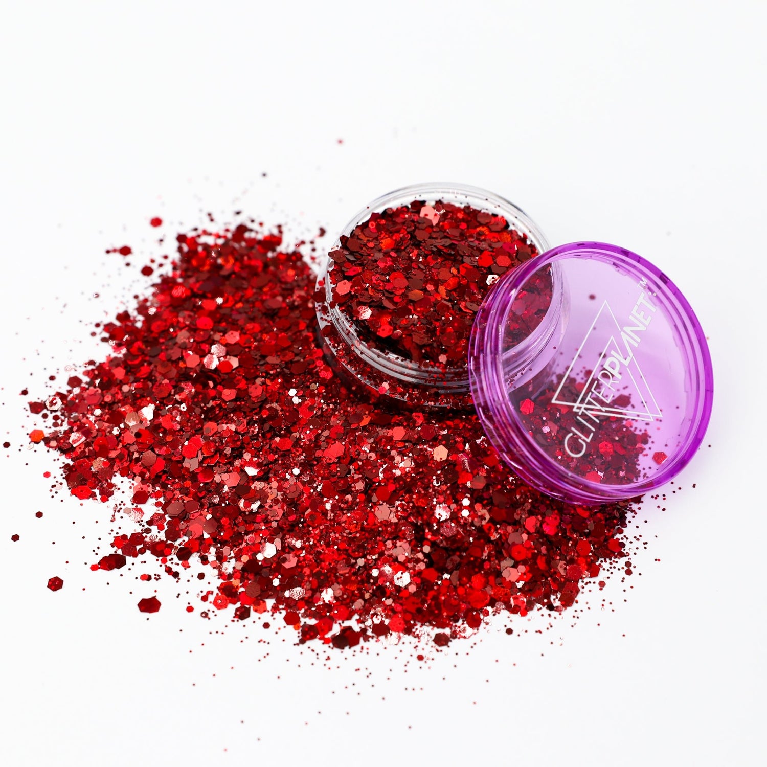 Red glitter flakes spilled on a white background next to an open clear jar and a purple lid with white text reading GLITTERPLANET