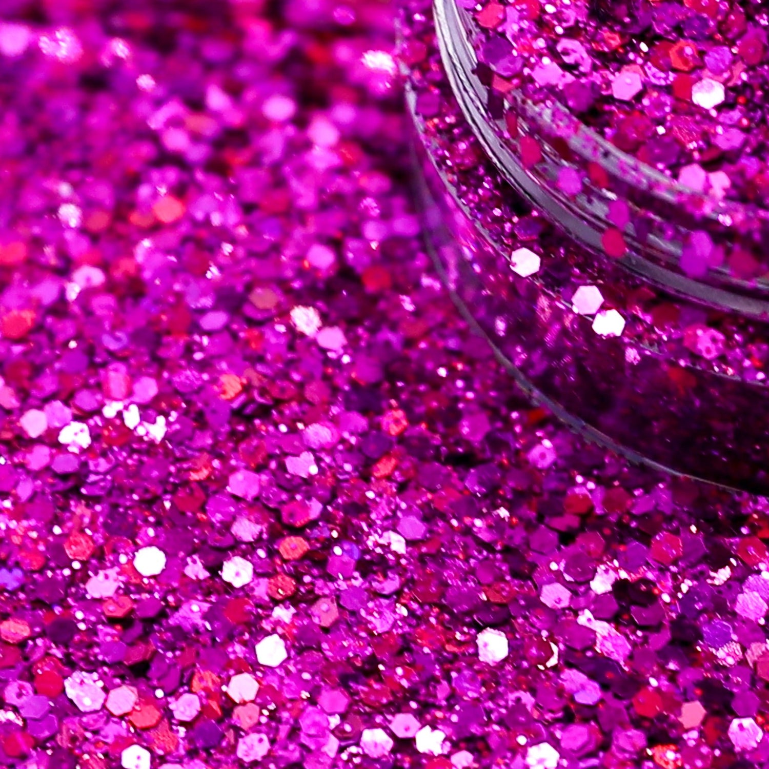 Close-up of pink glitter with a jar partially filled with glitter.