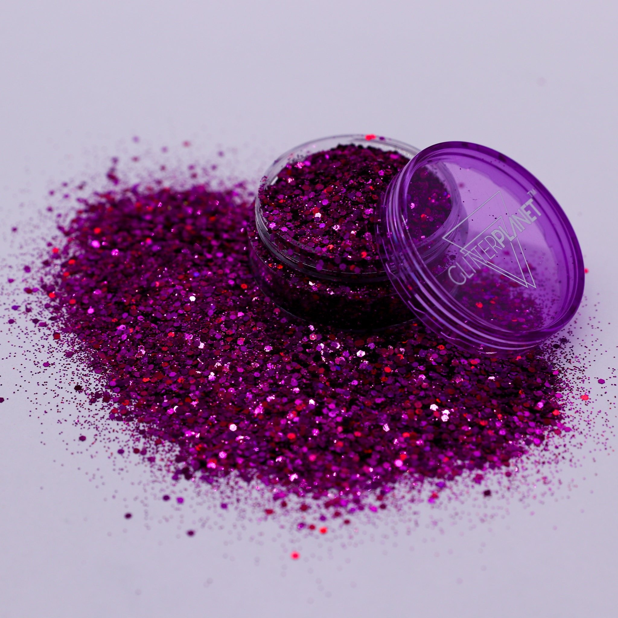 Purple glitter with an open container on a light gray background