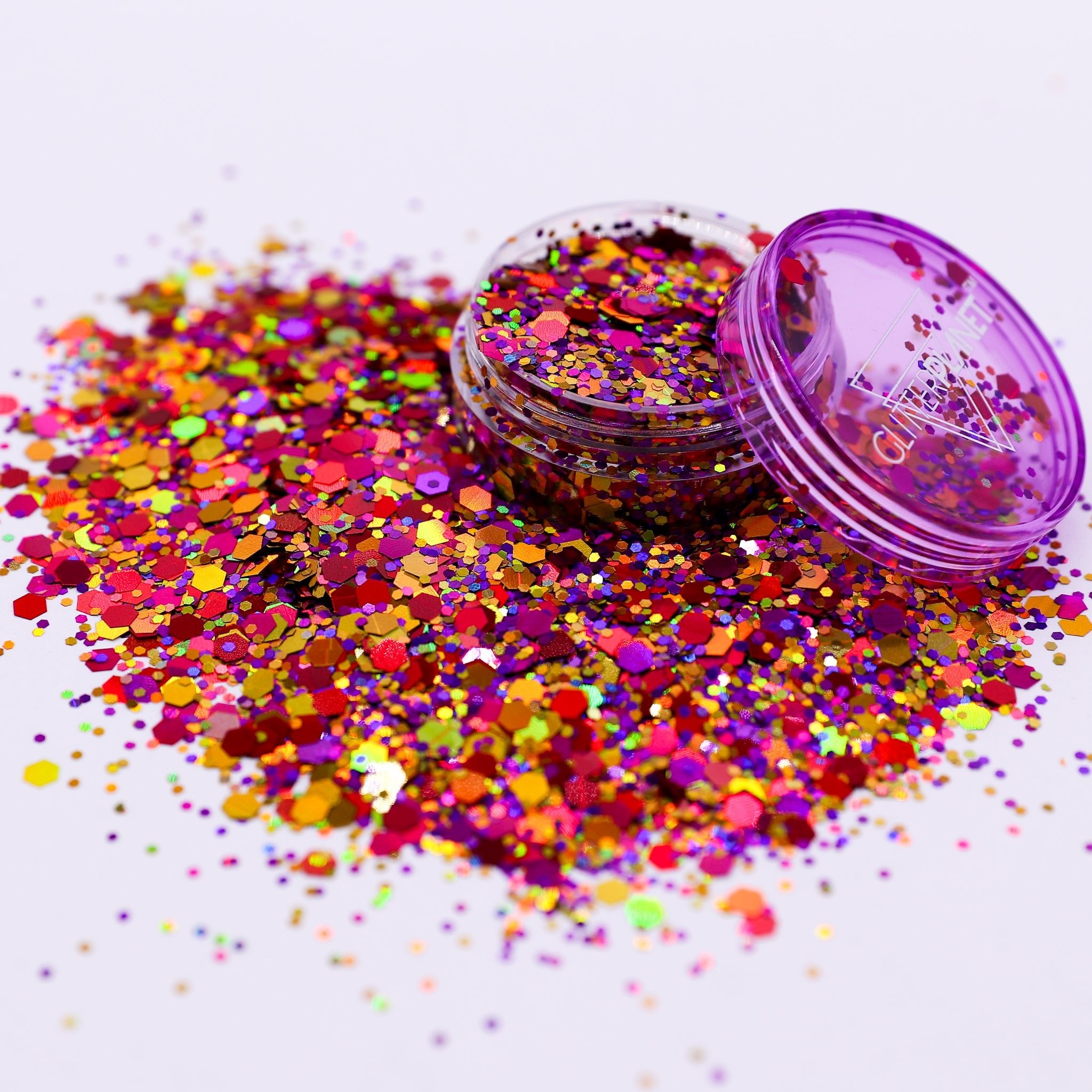 Colorful glitter scattered on a white background with an open container of glitter.
