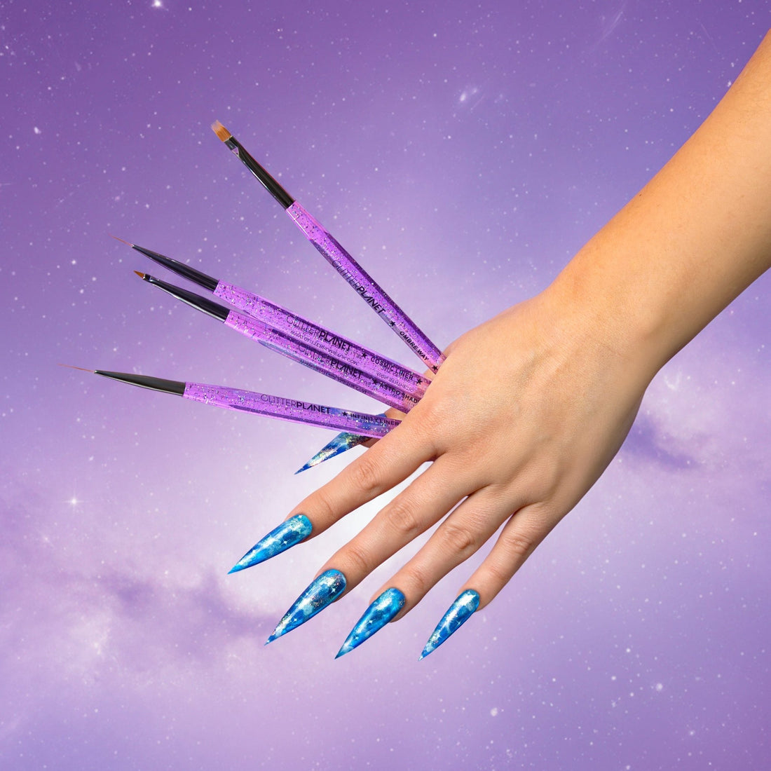 Hand with blue nail polish holding purple nail art brushes against a purple background