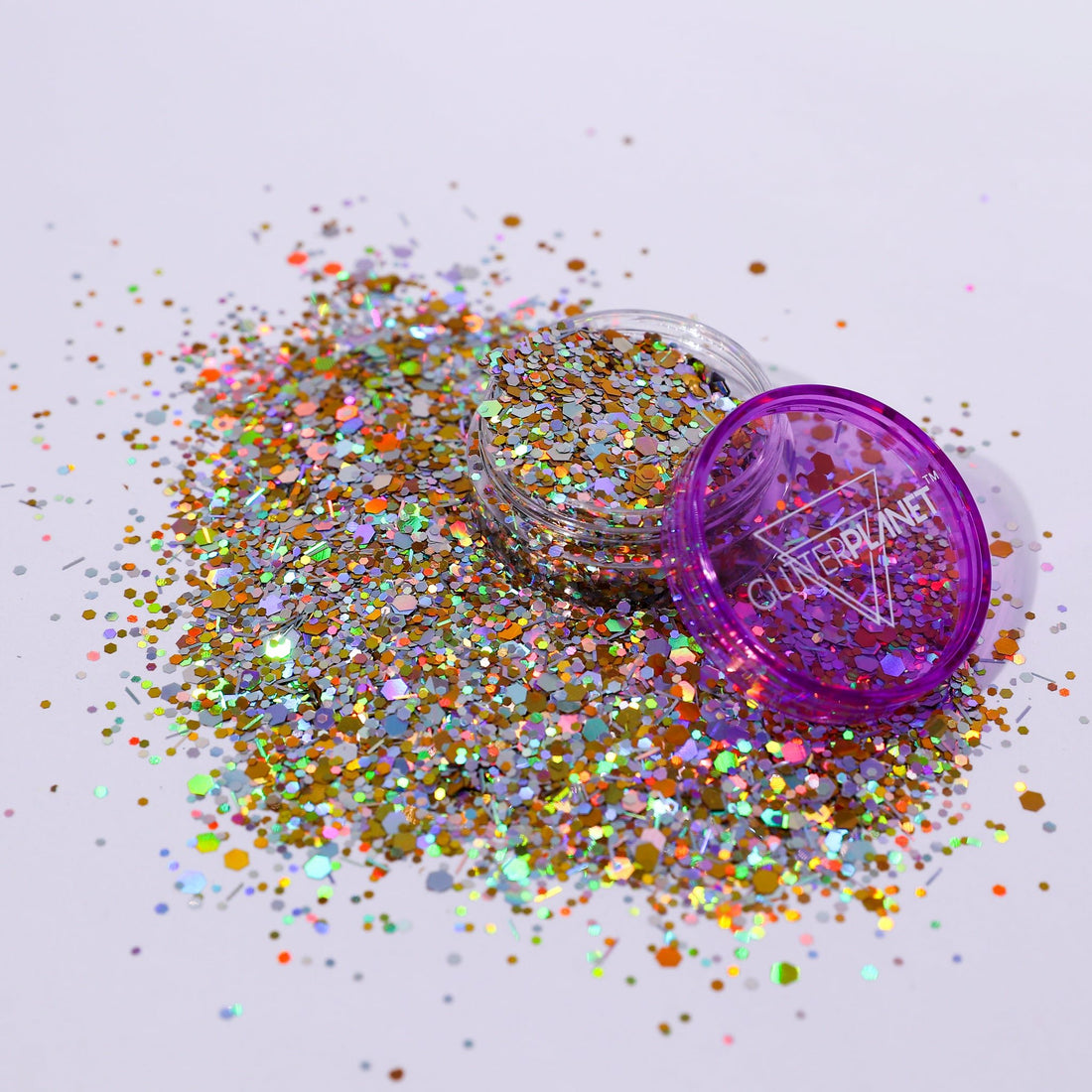Purple glitter container with scattered glitter on a light gray background