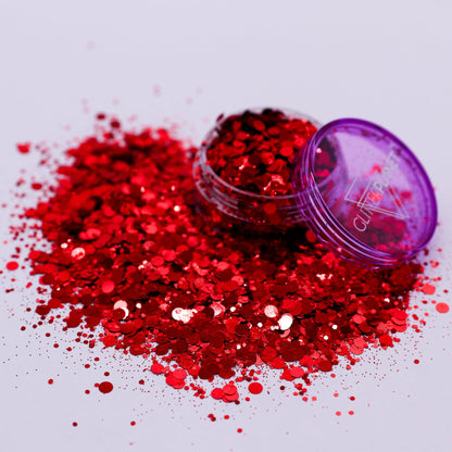 Red glitter spilling out of a purple container on a white background