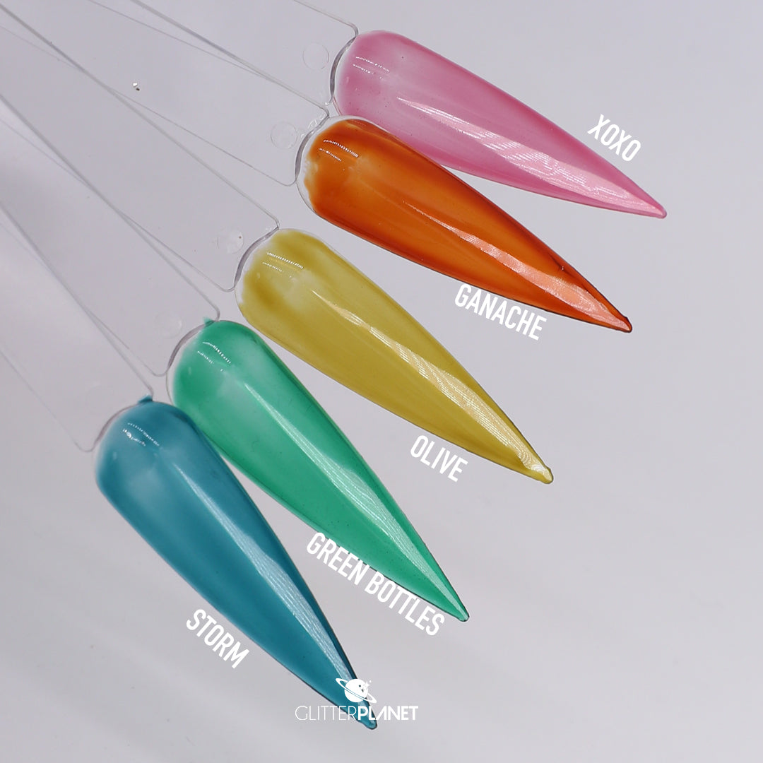 Six glossy nail color swatches on clear plastic sticks, labeled XOXO, Ganache, Olive, Storm, Green Bottles, and a blue shade, arranged diagonally on a light gray background.