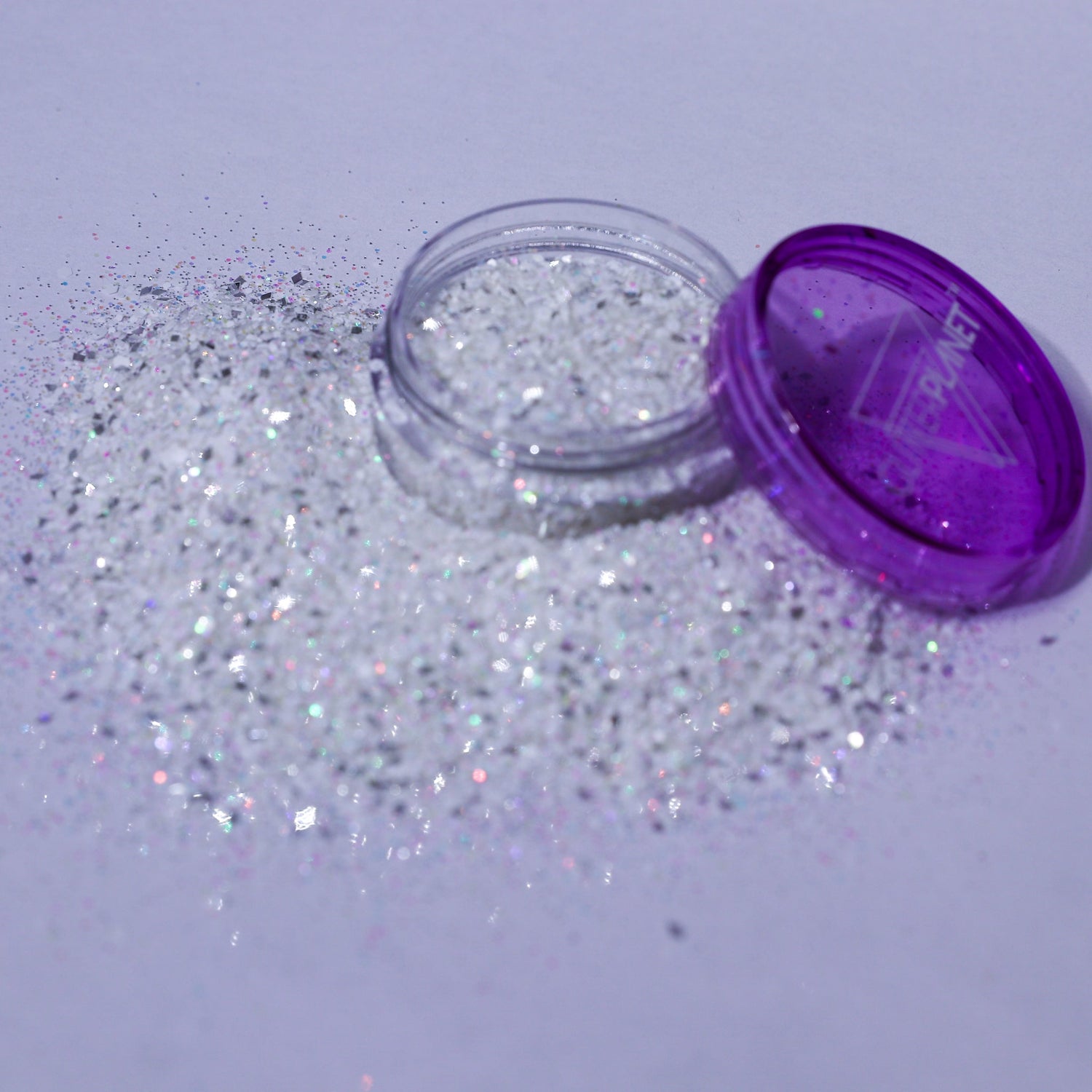 Open container of glitter with purple lid on a light gray background