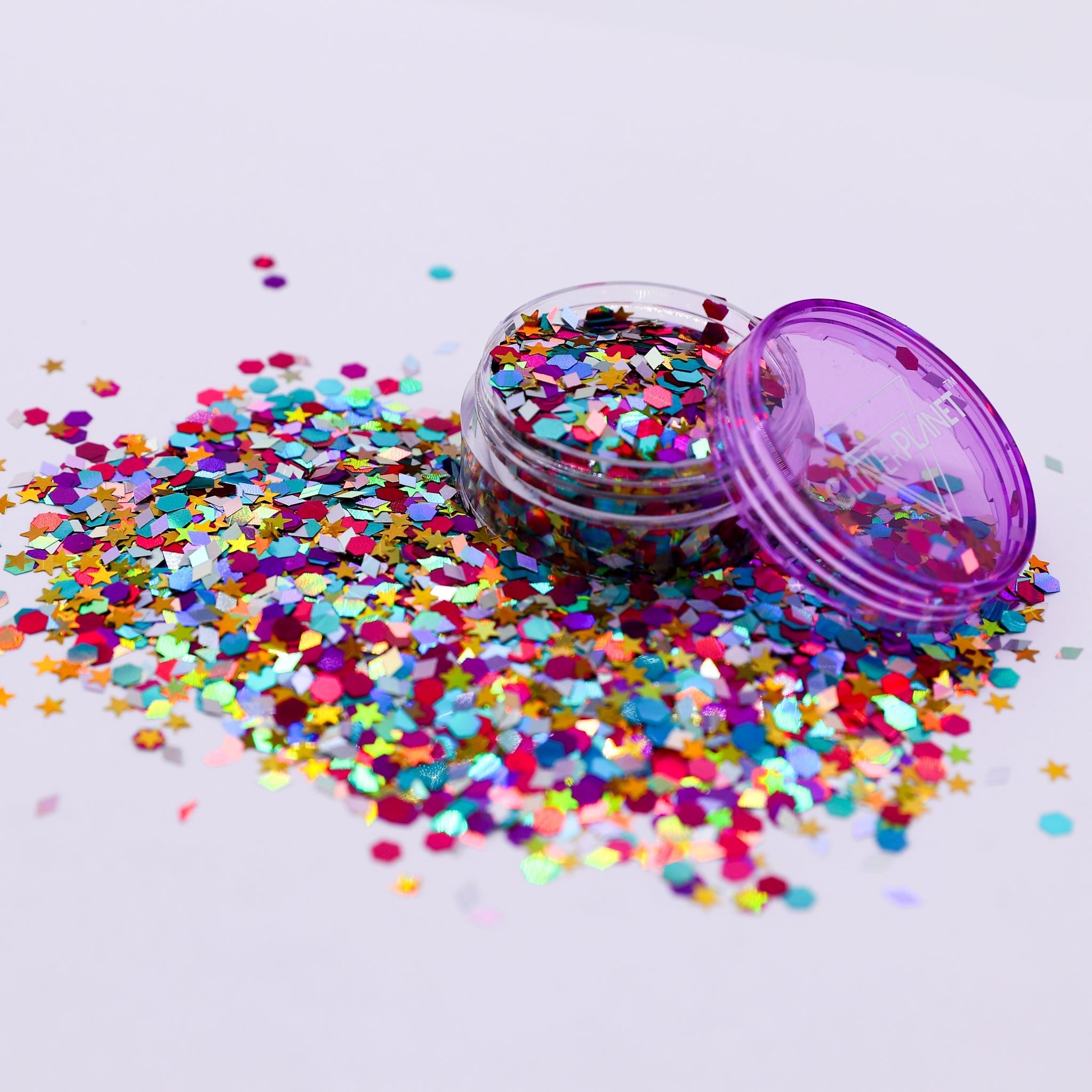 Colorful confetti scattered around a small container with a purple lid on a light gray background | Glitter Planet